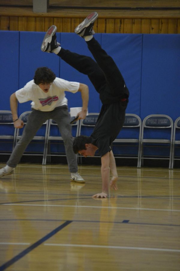 Two senior students next to one another, with one doing a handstand