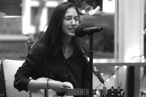 female teenager sings into a microphone while playing a ukulele