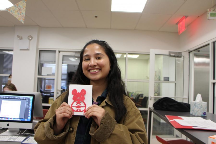 Teenage girl holds up a paper cut-out of a rat.