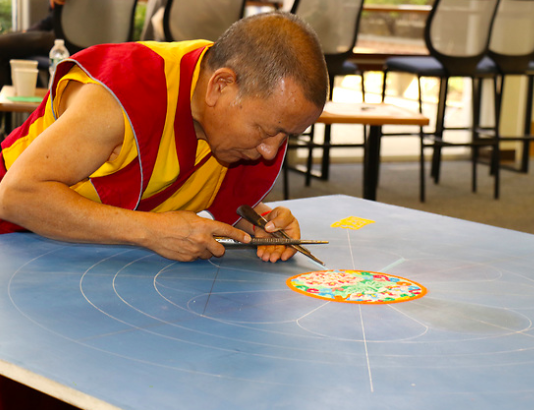 Lama Tenzin while creating the mandala in the library